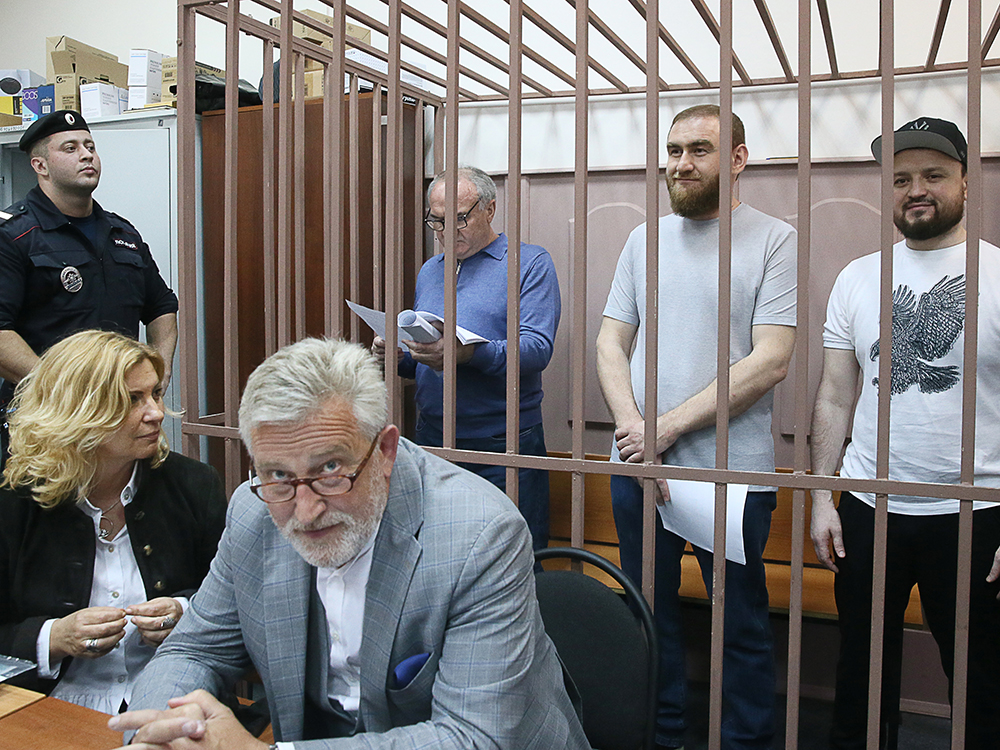 За решеткой в зале суда оказался бывшей сенатор от Карачаево-Черкесии Рауф Арашуков (в центре) вместе со своими родственниками: отцом Раулем (слева) и братом Русланом (справа). Так они встречали продление своего ареста. Экс-сенатора задержали зимой прямо во время заседания Совета Федерации. Следствие настаивает, что он причастен к организации двух убийств. Его также обвиняют в давлении на свидетеля убийства и участии в преступном сообществе. В мае Совфед лишил Рауфа полномочий. Свою вину он не признает.