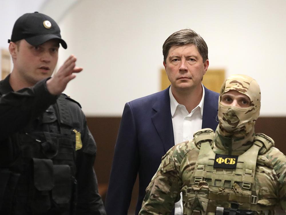 Сотрудник ФСБ и судебный пристав в бронежилетах проводят экс-владельца банка «Югра» Дмитрия Хотина в зал суда. Через пару часов бизнесмена отправят под домашний арест по делу о растрате 7,5 млрд руб. Ещё летом 2017-го банк потерял лицензию, «дыра» в его капитале превысила 160 млрд руб. «Югру» признали банкротом. По версии ее временного управляющего, руководство банка выводило из него активы под видом кредитов. Из всех займов, которые выдавала «Югра», 98% направлялись на финансирование других бизнесов Хотина, утверждает АСВ.